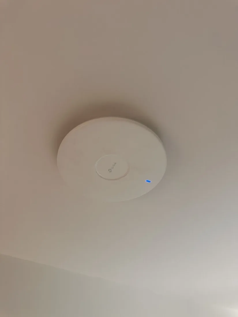 A ceiling-mounted UniFi wireless access point installed flush to the ceiling.