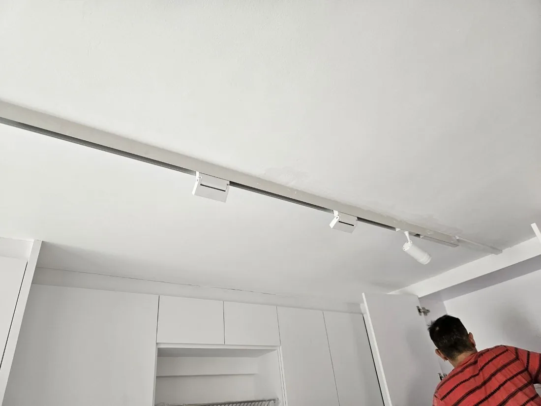 A slim linear ceiling light running the length of a room above fitted cabinetry.