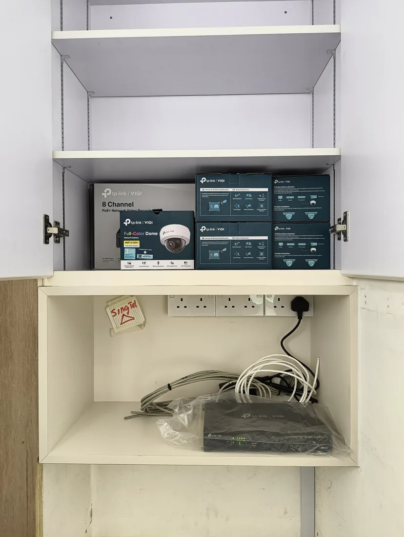 Network switches and a router stacked on a cupboard shelf, with patch cables run to them.