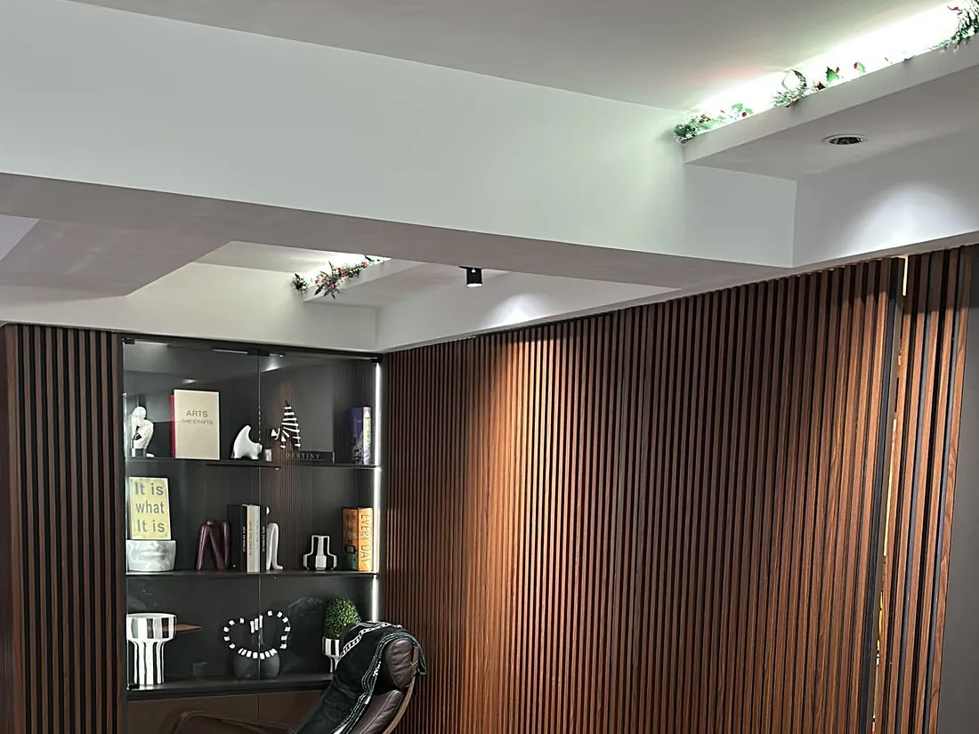 Living area at Stirling Road with cove lighting, a backlit display cabinet and a slatted timber feature wall