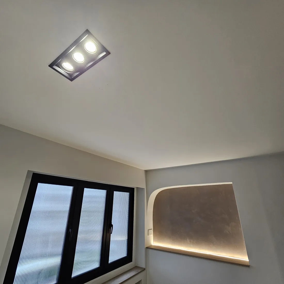 Recessed adjustable spotlights and a backlit curved alcove in the Woodlands flat