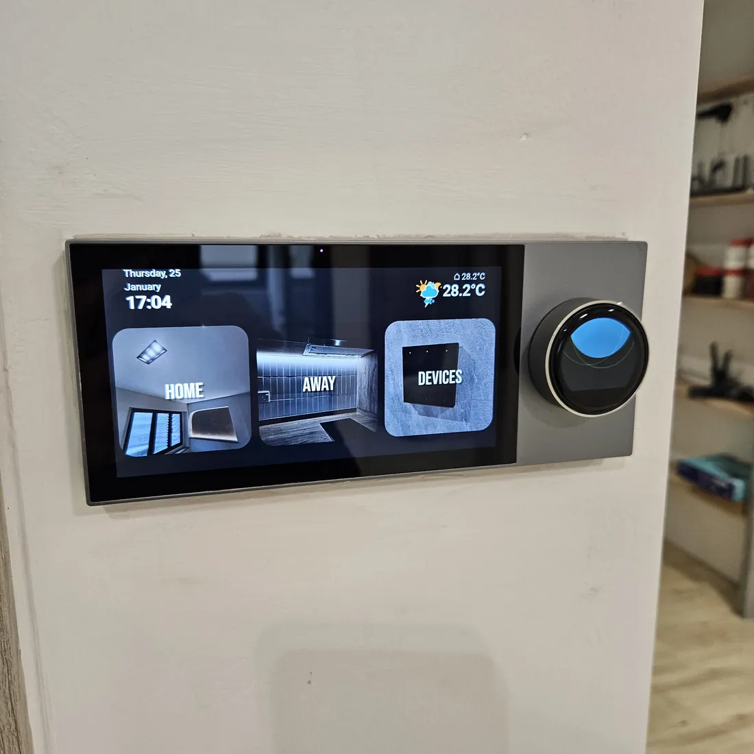 Wall-mounted smart home control panel at Woodlands showing Home, Away and Devices scenes with a rotary dial beside it
